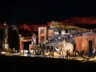 Bühnenbild mit einem riesigen Sarkophag, einem ägyptischen Tempel, einem Obelisken und einem brennenden Elefanten, Wasserbecken und Pyrotechnik