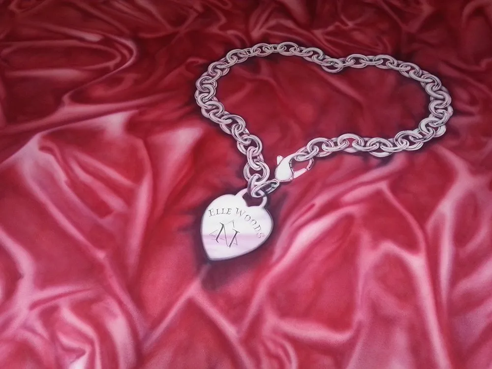 Nahaufnahme: Silbernes Armband mit Kettengliedern, Herz mit "Elle Woods" Schriftzug