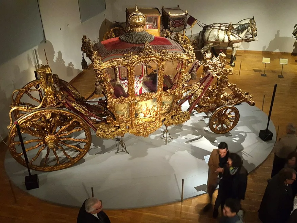 Ausstellungsraum: Prächtige goldene Kutsche mit roter Polsterung und Pferden
