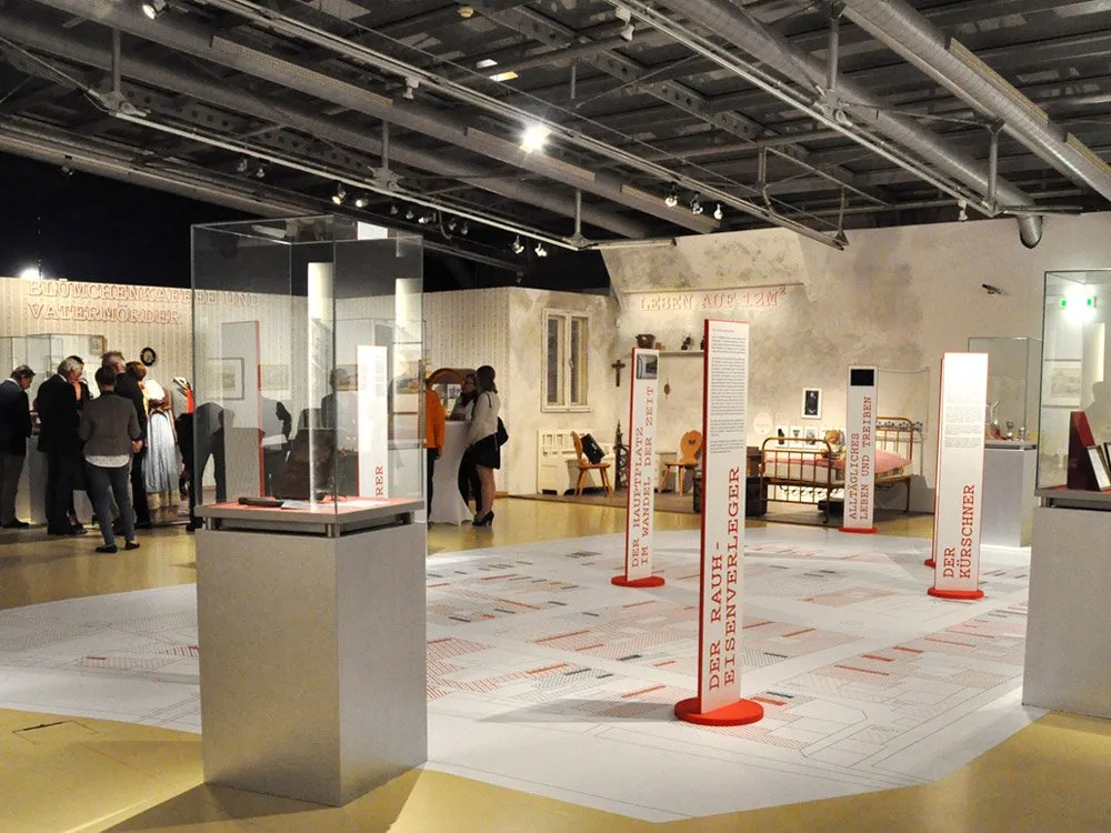 Ausstellungsraum: große Karte am Boden zeigt Leobens Geschichte. Besucher umgeben Vitrinen und Schilder mit Texten 