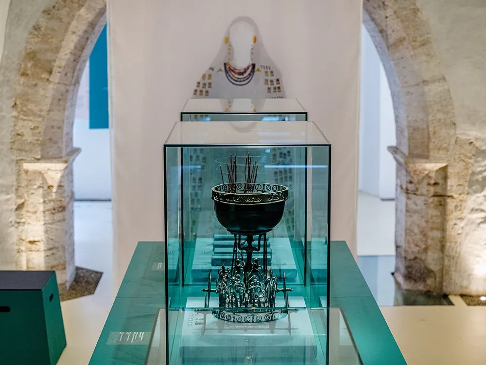 Ausstellung mit steinernen Rundbögen, zentrale Glasvitrine mit antikem Gefäß