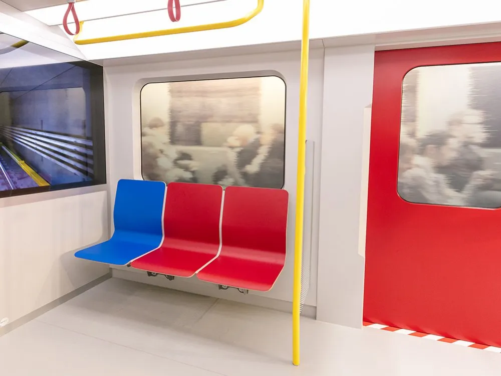 Innenraum X-Waggon: Ein blauer neben zwei roten Sitzen, gelbe Haltestange