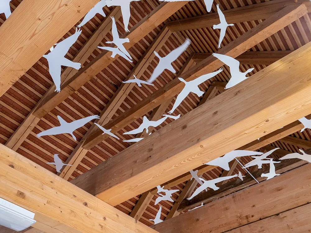 Weiße Vogelsilhouetten hängen unter dem Holzdach