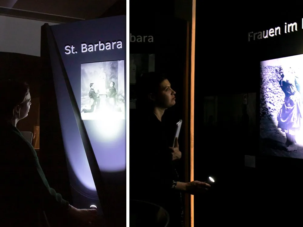 Zweiteiliges Bild: Links eine Person mit Taschenlampe an der Station „St. Barbara“ mit historischem Bild; rechts eine Person mit Taschenlampe an der Station „Frauen im Bergbau“ mit Foto.