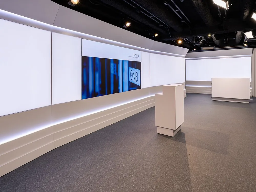 Studio mit LED-Wand mit und weißem Pult, aus einer seitlich-linken Perspektive