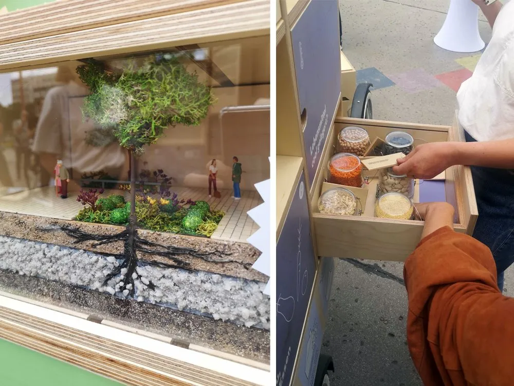 Detailansicht: Links ein Modell mit einem grünen Baum, Wurzeln und kleinen Figuren auf einer Schicht aus Erde und Steinen. Rechts eine Hand, die eine Schublade mit verschiedenen Körnern und Samen aus einem E-Lastenfahrrad öffnet.