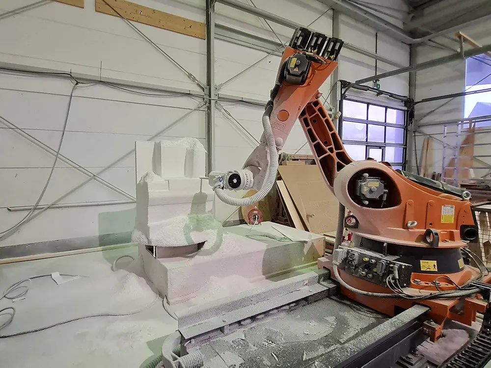Werkstattraum mit einem Roboterarm, der an einem Modell arbeitet