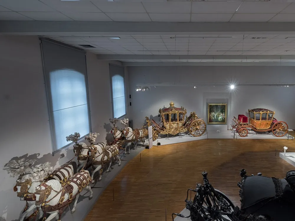 Ausstellungsraum: Prächtige goldene Kutsche mit Pferden, eine rote Kutsche und ein Gemälde an der Wand