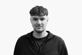 Halbportrait in schwarz-weiß: Junger Mann mit dunklen Haaren und Bart